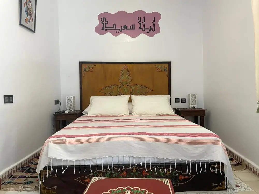 Double room with carved wooden headboard at Riad Tingis Tangier