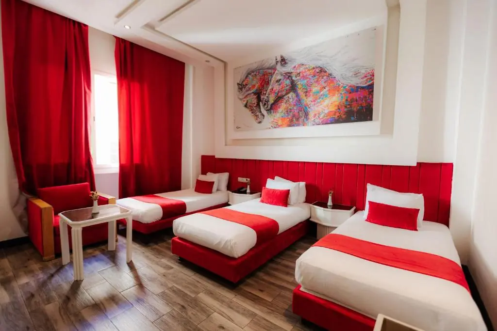 Triple room with three single beds and red accents at Windsor Hotel City Center Casablanca